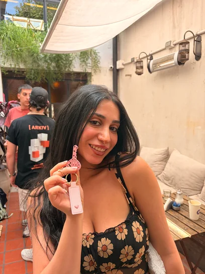 Jessy holding up her pink Babes Net key on a plant-filled terrace
