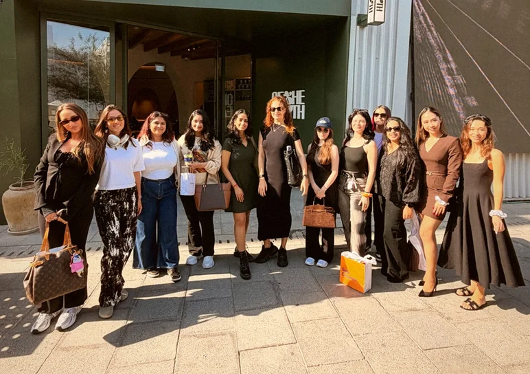 Eleven women lined up on a sunlit pavement outside the restaurant