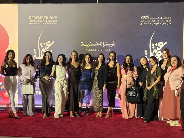 Thirteen women in evening dress on the red carpet in front of the Arabic Opera backdrop