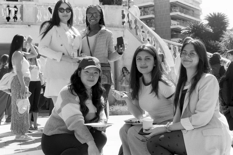 Five women with plates and coffee on the terrace steps, in black and white